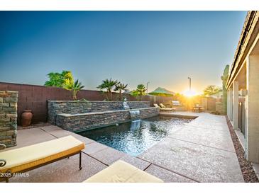 A tranquil pool area with waterfall feature, lounge chairs and lush landscaping creates an inviting backyard retreat at 3597 W Mineral Butte Dr, San Tan Valley, AZ 85144