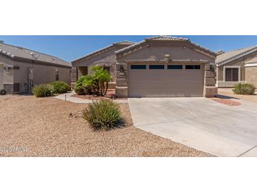 Tan home featuring a two-car garage and desert landscaping at 12132 W Caribbean Ln, El Mirage, AZ 85335