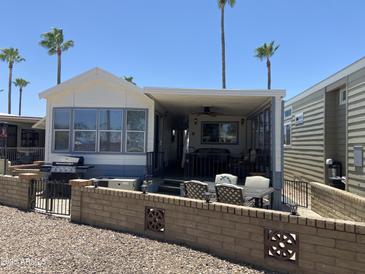 Charming mobile home with a cozy covered patio and well-maintained landscaping with palm trees at 2290 S Seminole Dr, Apache Junction, AZ 85119
