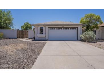 A cozy single-story home showing the garage, arched window and low maintenance landscaping at 3701 W Villa Maria Dr, Glendale, AZ 85308