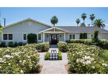 Charming single-story home featuring a symmetrical facade, gray siding, and a beautifully landscaped front yard with a small fountain at 4125 N 64Th St, Scottsdale, AZ 85251