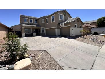 Two-story home features a three-car garage and a long driveway with basketball hoop at 10347 W Odeum Ln, Tolleson, AZ 85353