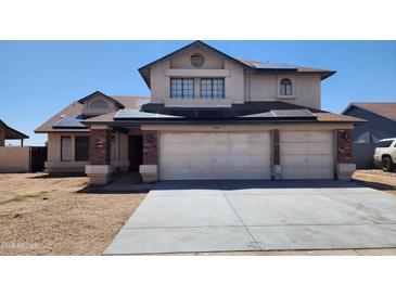 Two-story home featuring a brick garage, solar panels, and low-maintenance front yard at 17458 N 64Th Dr, Glendale, AZ 85308