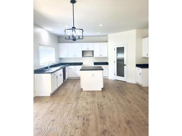Bright kitchen with an island, white cabinets, modern lighting, and dark countertops at 2114 N 94Th Ave, Phoenix, AZ 85037