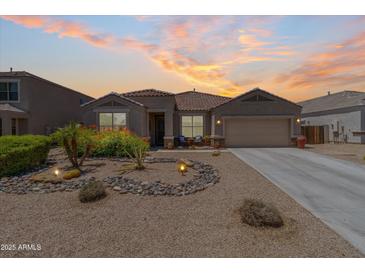 Charming single-story home featuring desert landscaping, a two-car garage, and a welcoming front porch with seating at 36130 N Quiros Dr, Queen Creek, AZ 85143