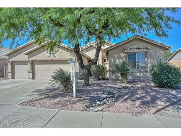Charming single-story home with a well-manicured front yard featuring desert landscaping and mature trees at 11580 N 86Th Ln, Peoria, AZ 85345