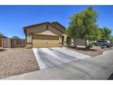 Tan single-Gathering home featuring a two-car garage, desert landscaping, and a tree-lined front yard at 20410 N Mac Neil St, Maricopa, AZ 85138