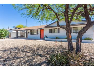 Charming single-story home featuring a white exterior, vibrant orange front door and desert landscaping at 3325 S Shafer Dr, Tempe, AZ 85282
