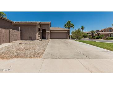 Beige single-story home featuring a wide driveway, a two-car garage and desert landscaping at 162 W Raven Dr, Chandler, AZ 85286