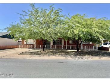 Charming brick home featuring mature trees, a white picket fence, and classic architectural details at 3006 W Stella Ln, Phoenix, AZ 85017