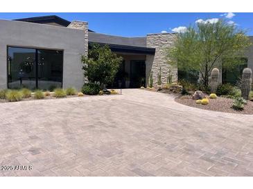 Desert landscaping and a paver driveway accent the exterior of this contemporary home at 38031 N 97Th Way, Scottsdale, AZ 85262
