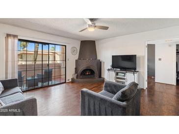 Bright living room features hardwood floors, unique fireplace, and sliding glass doors to the patio at 10410 N Cave Creek Rd # 2229, Phoenix, AZ 85020