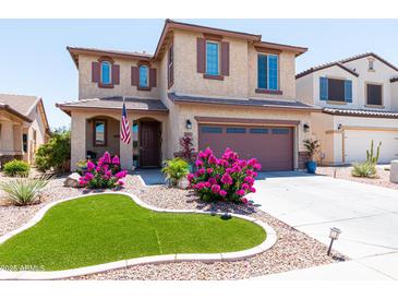 Charming two-story home featuring a well-manicured yard with vibrant pink flowers and decorative turf at 19461 N Rose Rd, Maricopa, AZ 85138