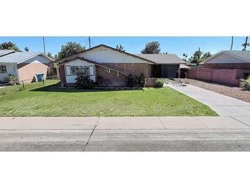 Charming single-Gathering home with a well-maintained lawn and mature landscaping, complemented by a long driveway at 3937 W Stella Ln, Phoenix, AZ 85019