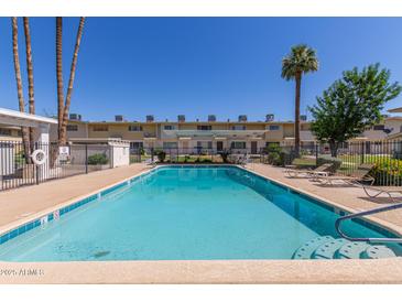 Community pool with clear blue water, surrounded by lounge chairs and manicured landscaping at 8211 E Garfield St # J219, Scottsdale, AZ 85257
