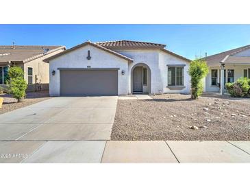 Charming single-story home with desert landscaping, covered entry, and gray two car garage door at 1120 W Desert Hollow Dr, San Tan Valley, AZ 85143