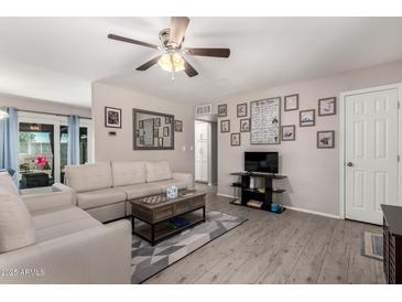 Bright living room with a ceiling fan, wood laminate floors, white couch, and stylish decor at 1531 W Campo Bello Dr, Phoenix, AZ 85023
