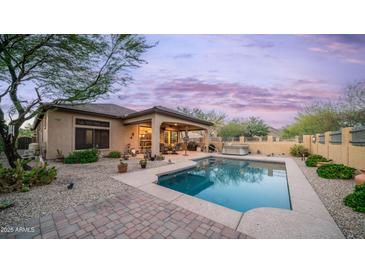 Inviting backyard oasis featuring a sparkling pool, covered patio, and desert landscaping, perfect for relaxation at 9037 E Indigo St, Mesa, AZ 85207