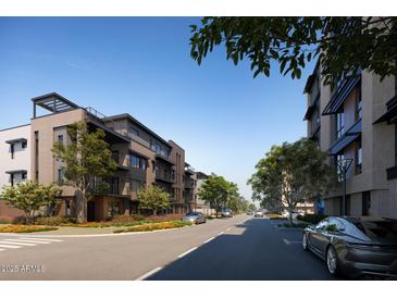 Modern townhomes with well-manicured landscaping lining a quiet street under a clear blue sky at 19360 N 73Rd St # 1058, Scottsdale, AZ 85255
