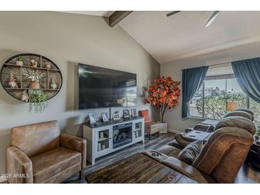 Comfortable living room features a vaulted ceiling, stylish furniture, and a decorative fireplace with a large screen TV at 6433 E University Dr, Mesa, AZ 85205