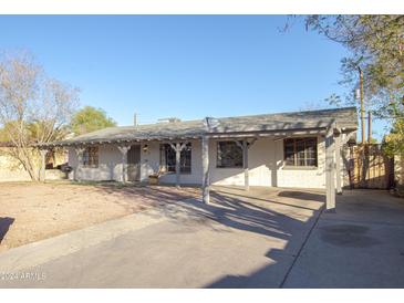 Single story house with a carport, painted white with gray trim and a gravel yard at 3418 W Roma Ave, Phoenix, AZ 85017