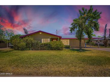 Charming single-story home featuring manicured lawn and mature shade tree under a colorful sky at 3936 E Oak St, Phoenix, AZ 85006