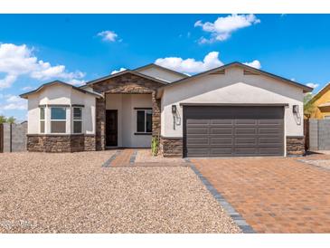 Charming single-story home featuring a stone facade, brick driveway, and two-car garage at 8226 W Swansea Dr, Arizona City, AZ 85123