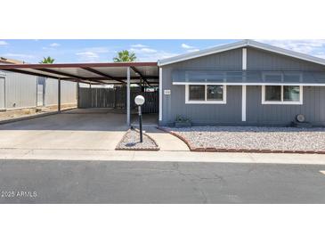 Charming single-story home featuring a covered carport, low-maintenance landscaping, and appealing gray siding at 10951 N 91St Ave # 184, Peoria, AZ 85345