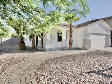 Charming single-story home with a desert landscape, palm trees, and inviting walkway at 1187 E Cowboy Cove Trl, San Tan Valley, AZ 85143
