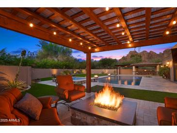 Inviting backyard with a fire pit, pool, jacuzzi, outdoor kitchen, and lush landscaping perfect for relaxing at 4518 E Solano Dr, Phoenix, AZ 85018