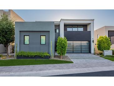 Modern home showcasing a sleek design with a glass garage door and manicured landscaping at 4544 N Evans Dr, Scottsdale, AZ 85251