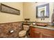Elegant powder room with a granite countertop, decorative mirror, and unique brown vessel sink at 12797 S 179Th Dr, Goodyear, AZ 85338