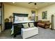 Spacious primary bedroom with a dark wood bed frame and a cozy seating area at 12797 S 179Th Dr, Goodyear, AZ 85338