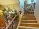 Carpeted stairs with decorative iron railing ascend past a green plant and a stone accent wall, enhancing the home's appeal at 12797 S 179Th Dr, Goodyear, AZ 85338
