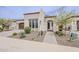 A beige single-Gathering home showcasing a landscaped front yard and an inviting, covered entryway with a dark door at 578 E Las Puertas Ln, Queen Creek, AZ 85140