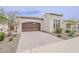 Beige home featuring a beautiful paver driveway leading to an attached two-car garage with a dark wood door at 578 E Las Puertas Ln, Queen Creek, AZ 85140