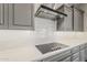 Close up of a modern kitchen with sleek cooktop, white backsplash, quartz countertops and stainless range hood at 578 E Las Puertas Ln, Queen Creek, AZ 85140