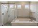 Main bathroom showcasing a glass shower with a tiled seat and a soaking tub beneath three windows at 578 E Las Puertas Ln, Queen Creek, AZ 85140
