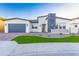 Modern home featuring a stone facade, neutral paint, manicured lawn, and a gray garage door at 7583 W Gelding Dr, Peoria, AZ 85381