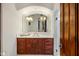 Bathroom featuring a marble countertop, dark wood cabinets, with an arched mirror, and a marble shower at 7533 N 70Th St, Paradise Valley, AZ 85253