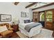 Comfortable bedroom with wood-beamed ceiling, ceiling fan, and access to an outdoor patio with stunning arched door at 7533 N 70Th St, Paradise Valley, AZ 85253