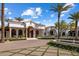 Stately white home featuring grand arches, lush landscaping, and a circular driveway with mature palm trees at 7533 N 70Th St, Paradise Valley, AZ 85253