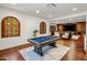 Spacious game room featuring a classic pool table, hardwood floors, and arched windows for natural light at 7533 N 70Th St, Paradise Valley, AZ 85253