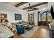 Living room with ceiling beams, ceiling fan, a sofa, and blue chairs, and an arched door at 7533 N 70Th St, Paradise Valley, AZ 85253