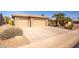 Two-car garage with tan colored doors and long driveway at 17156 W Lachlan Ct, Surprise, AZ 85387