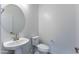 This powder room features a pedestal sink, round mirror, and toilet at 17463 N 66Th Ave, Glendale, AZ 85308