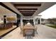 Elegant outdoor dining area with wood-beamed ceiling and views of the kitchen and beautifully landscaped yard at 6512 E Hummingbird Ln, Paradise Valley, AZ 85253