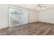 Spacious living room with wood flooring, ceiling fan, and sliding glass door to backyard at 1673 W Hazelwood St, Phoenix, AZ 85015