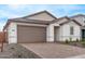 Inviting home featuring a two-car garage, manicured landscaping, neutral tones, and a brick driveway at 18795 E Elizar Dr, Gold Canyon, AZ 85118
