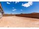 Large dirt backyard enclosed by a brick fence, with views of neighboring houses under a blue sky at 18507 E Camila Dr, Gold Canyon, AZ 85118